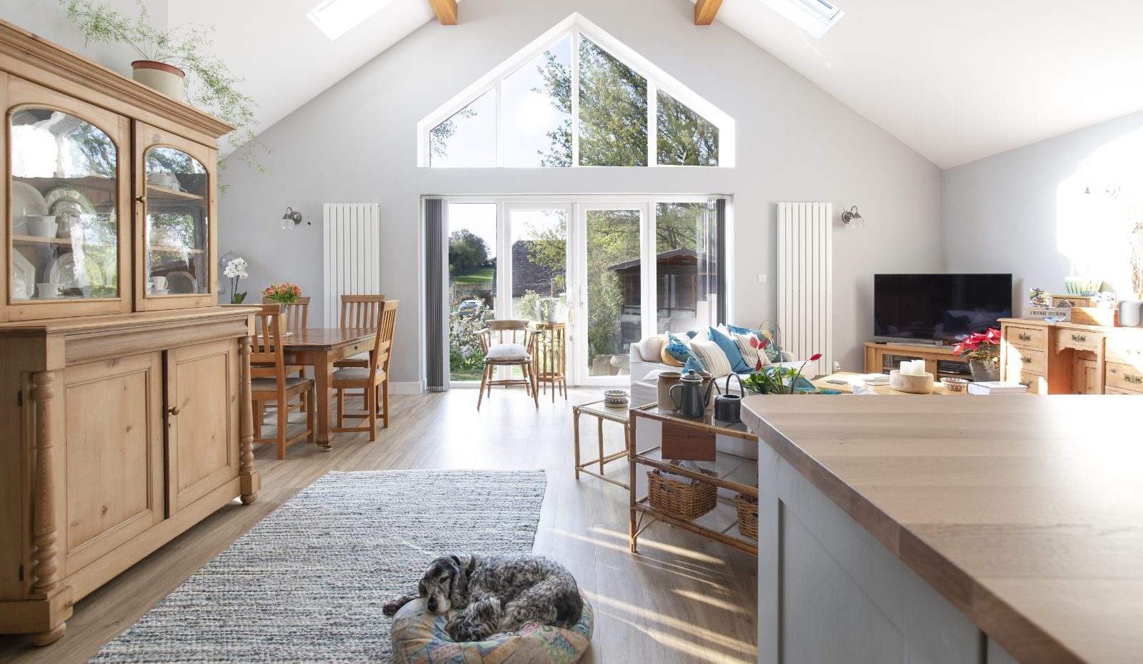 Open-plan kitchen extension with pale oak cabinetry, stone island and Crittall-style doors to garden