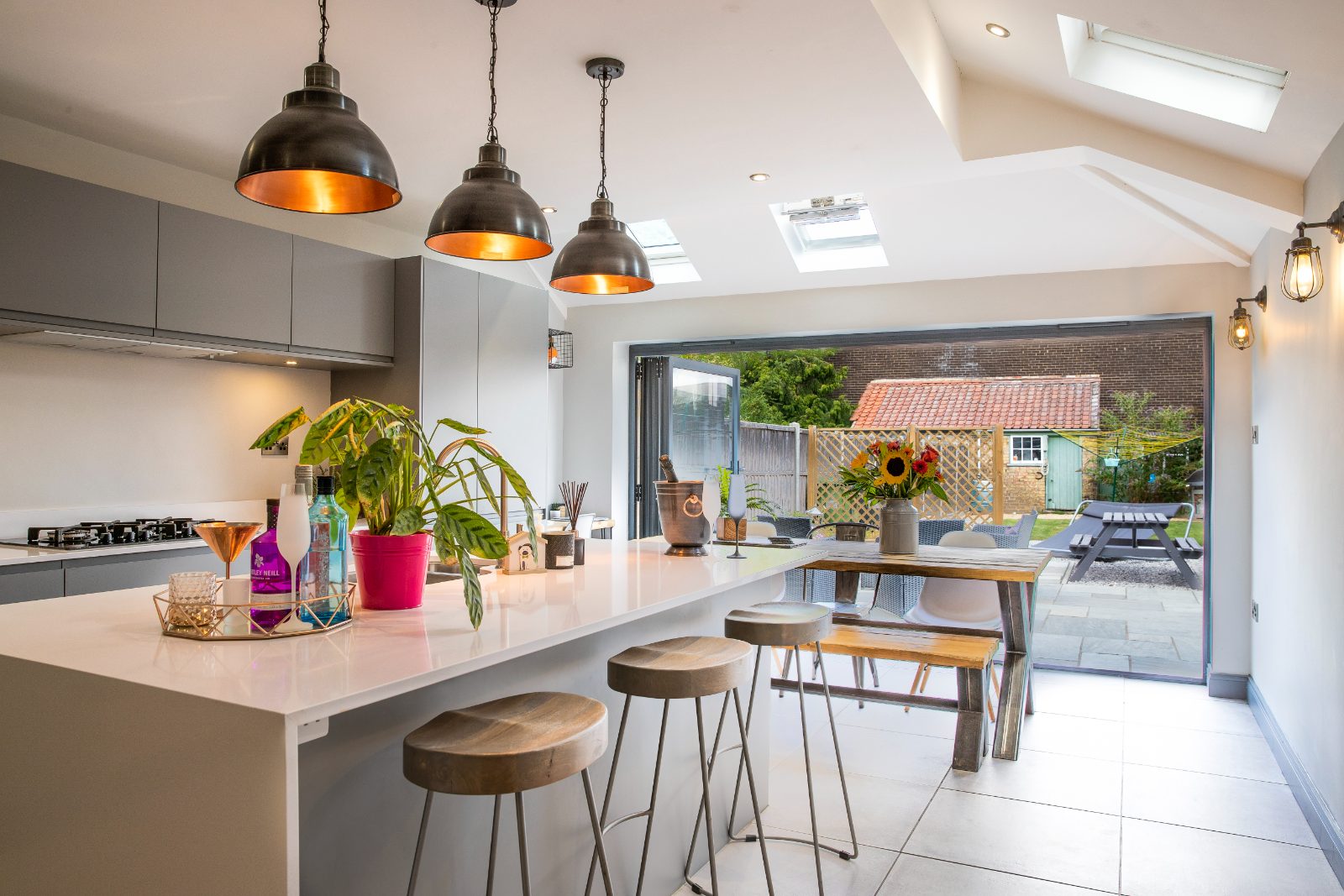 Open-plan kitchen extension with pale oak cabinetry, stone island and Crittall-style doors to garden