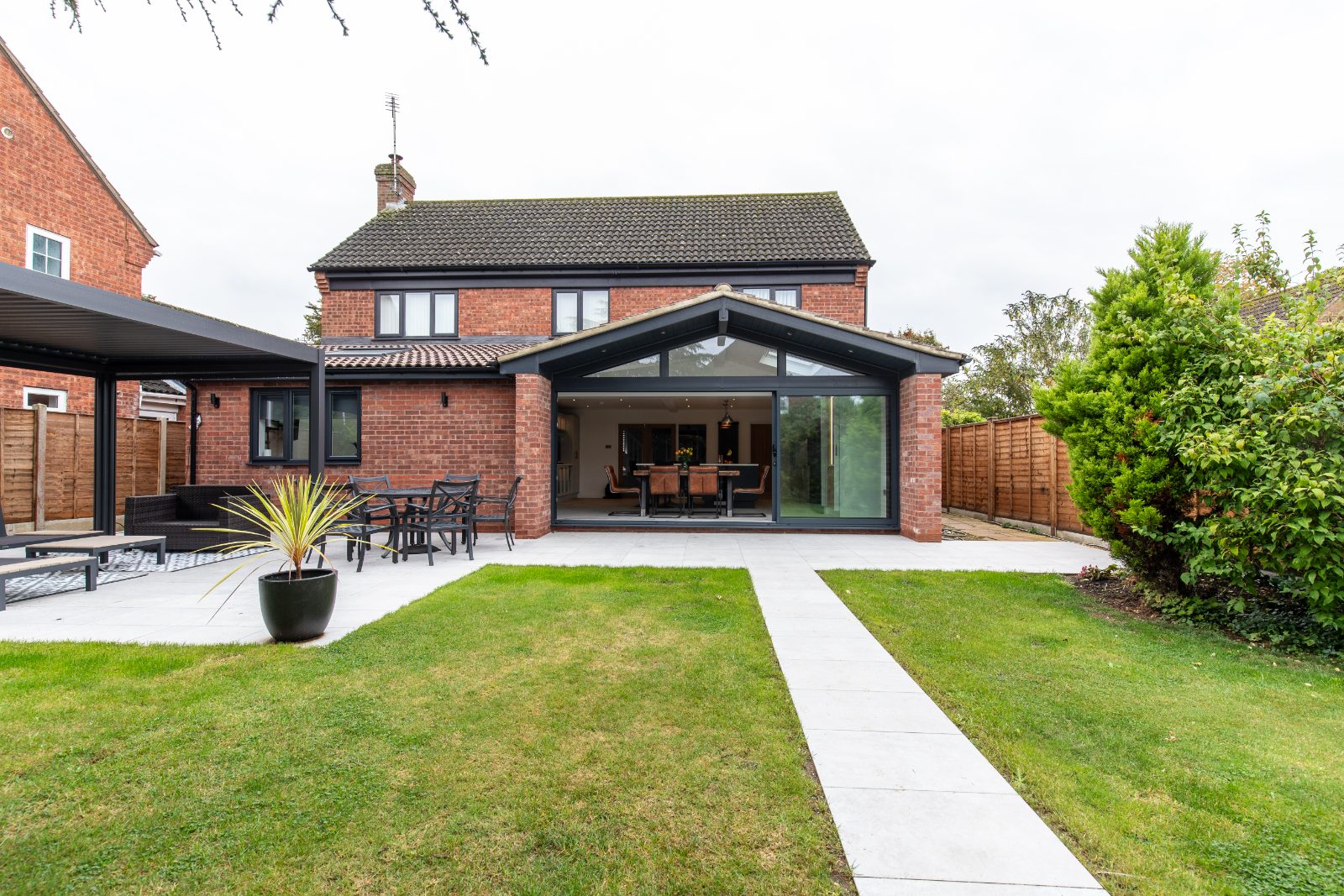 The finished glass gable kitchen extension in St Neots, viewed from the garden and showing large sliding doors under a vaulted roofline.