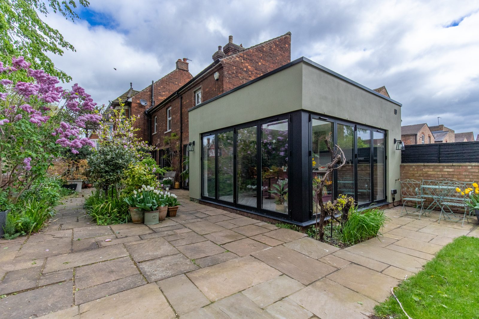 The new modern orangery extension with black-framed corner bifold doors open to the garden.