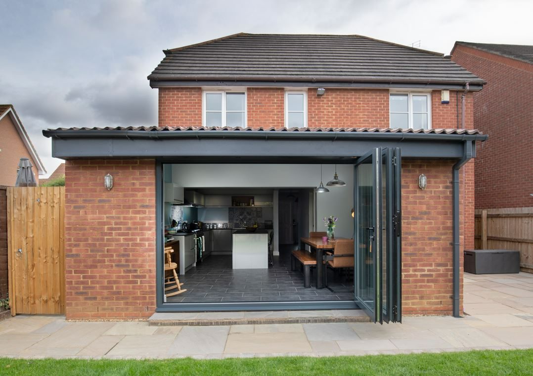 The new rear extension in Kettering, showing dark grey bi-fold doors opening from the kitchen diner onto the patio and garden.