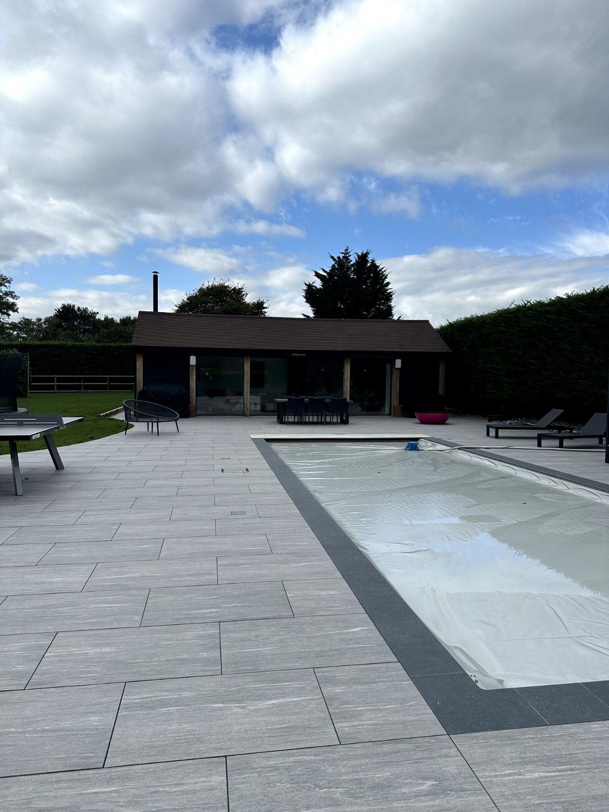 View from the pool house interior, across the patio and swimming pool towards the main listed building in Bedford.