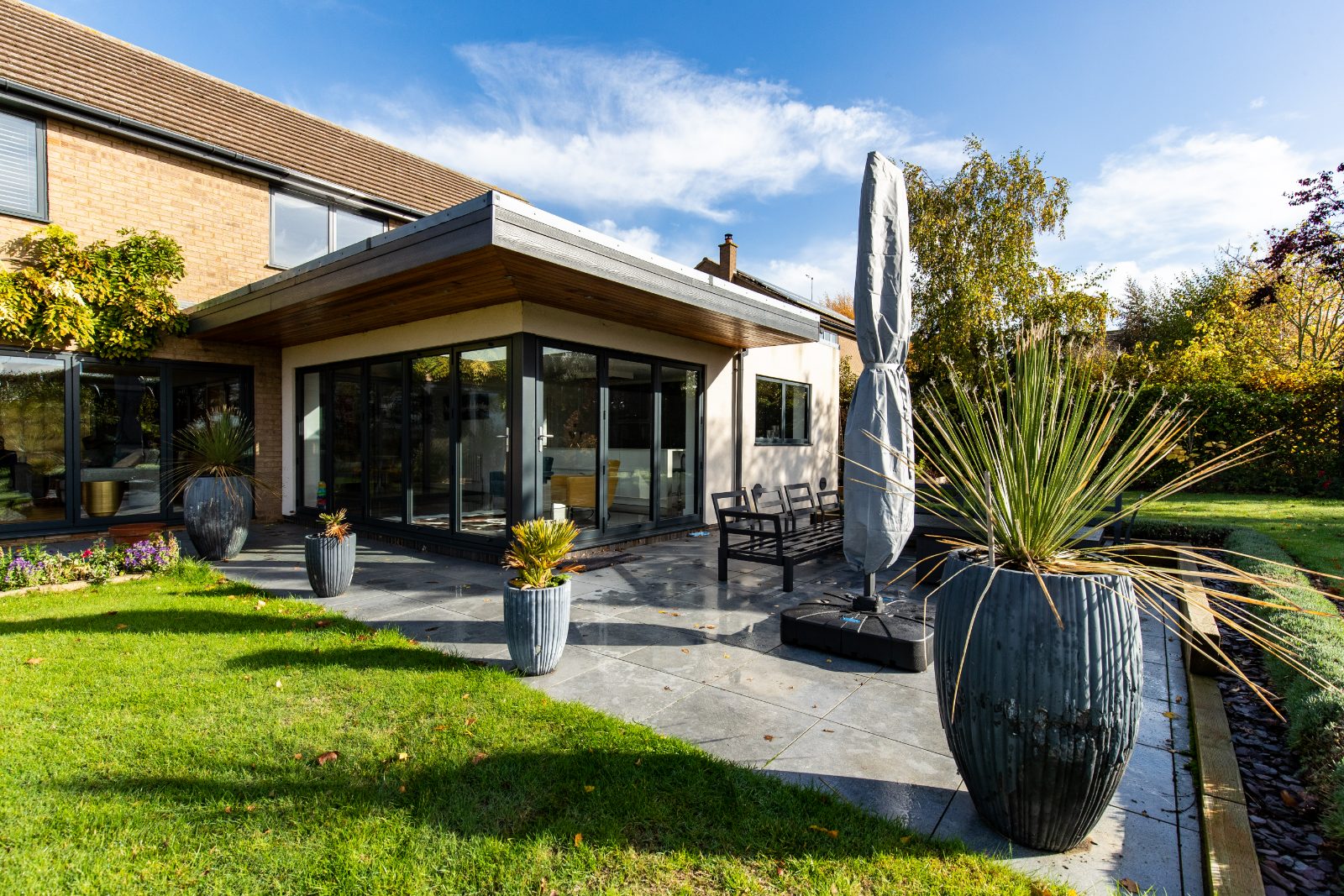 Rear exterior of a modernised Huntingdon home with a cantilevered roof extension and large glass doors leading to a patio.