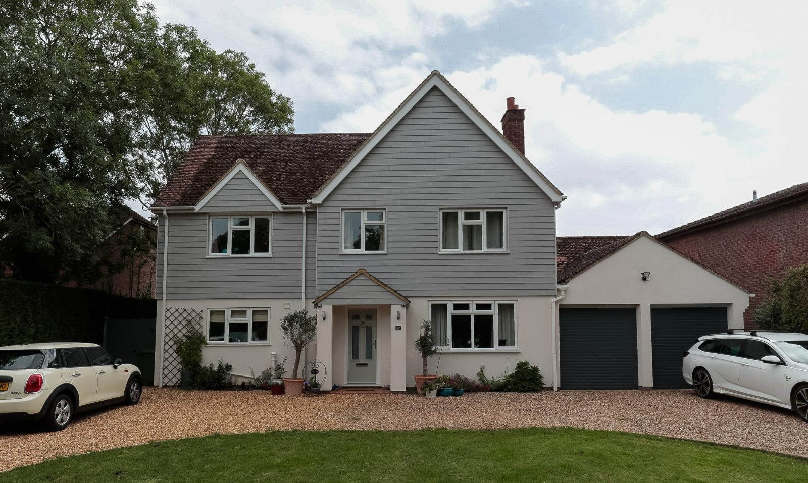 The transformed exterior of a five-bedroom family home in Houghton Conquest, featuring new grey cladding and a reconfigured entryway.